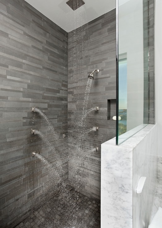 Norstone Grey Basalt Lynia Interlocking Tile installed on the walls of a walk in shower with seven shower heads in a modern styled bathroom in Miami